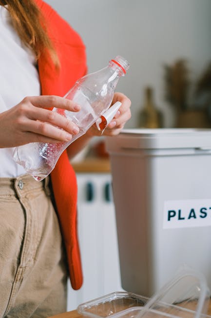 Two individuals are engaged in packing or sorting items during a home relocation, seated around large transparent plastic removal bins in an indoor setting. One person, wearing a blue long-sleeve shir